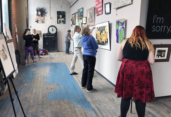 Four Hastings College students win prizes at art show 1 Students in a gallery hanging art for a show.