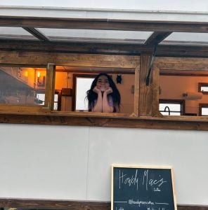 Person in the window of a trailer that serves coffee.