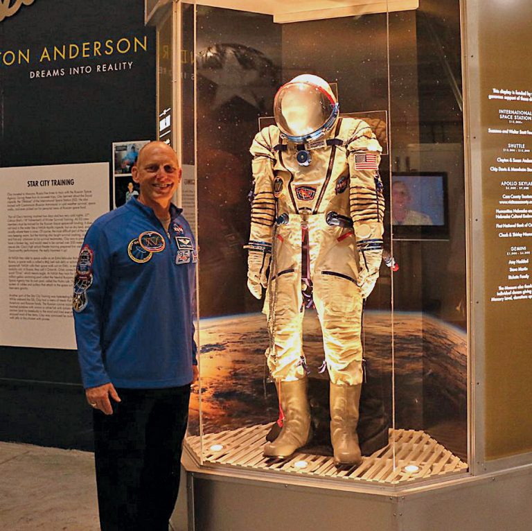 A photo of Clayton Anderson with a spacesuit he wore on the Space Station.