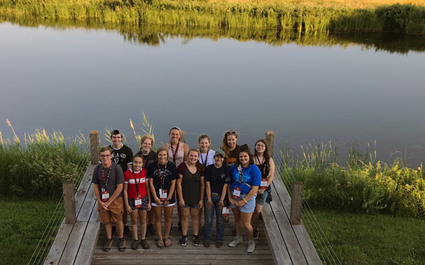 Students on a dock beside a river.