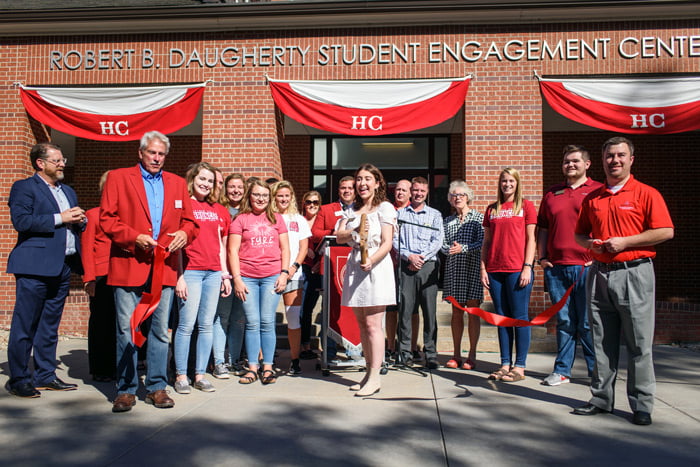 Group of people with a student cutting a ribbon for a building dedication.