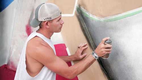 Derek Rusher spray painting a mural