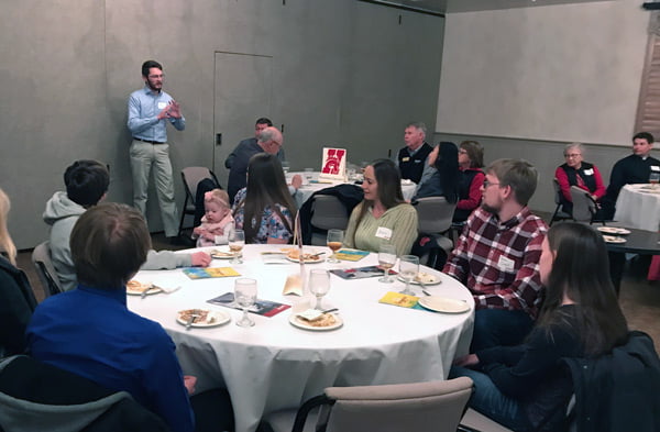 Student speaking in front of round tables.