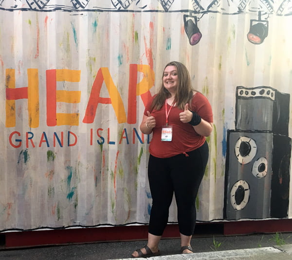 Student in front of a painted stage backdrop.