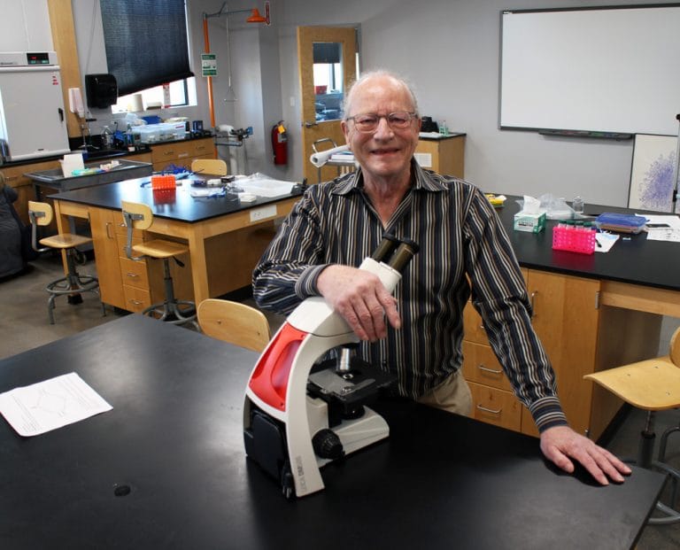 Dr. John Bohmfalk in a lab with a microscope.