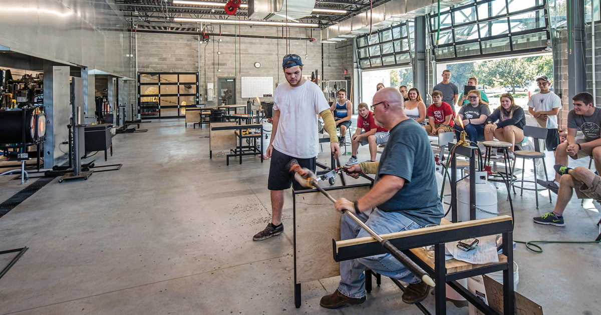 Photo of Tom Kreager and students in a glass studio.