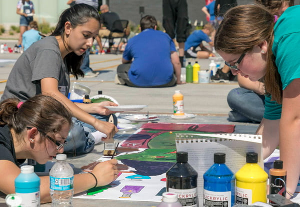 Students outside painting a mural.