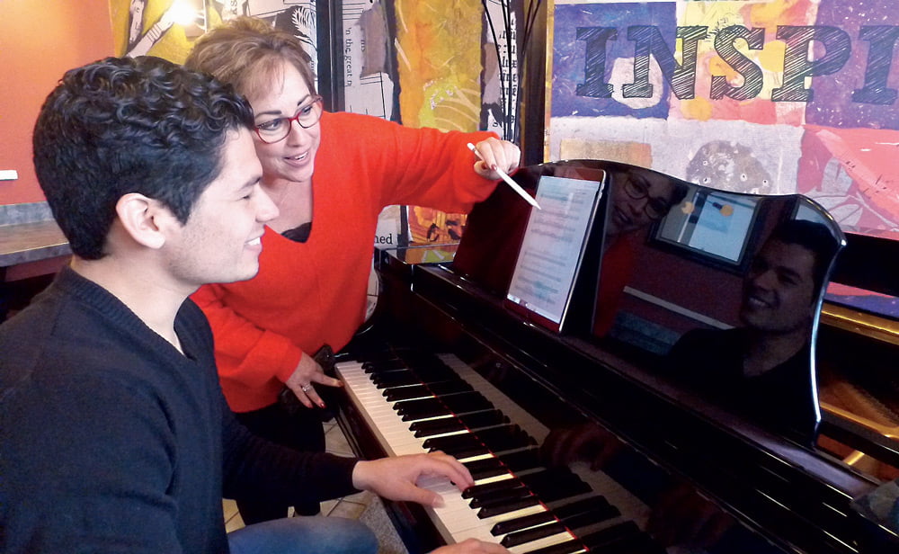 Dr. Hillary Watter working with a student at a piano.