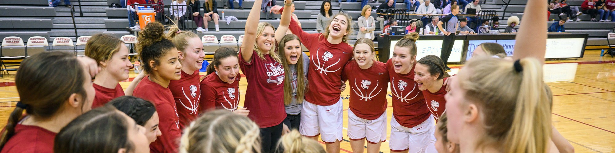 Why Hastings College 5 Hastings College women's basketball team cheering in a circle.