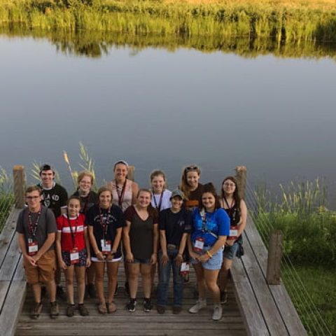 Students on a dock beside a river.