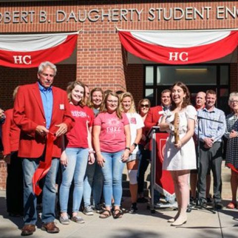 Student cutting a ribbon for a building dedication.