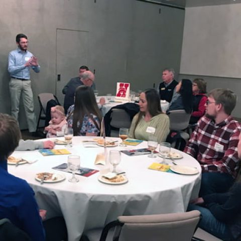 Student speaking in front of round tables.