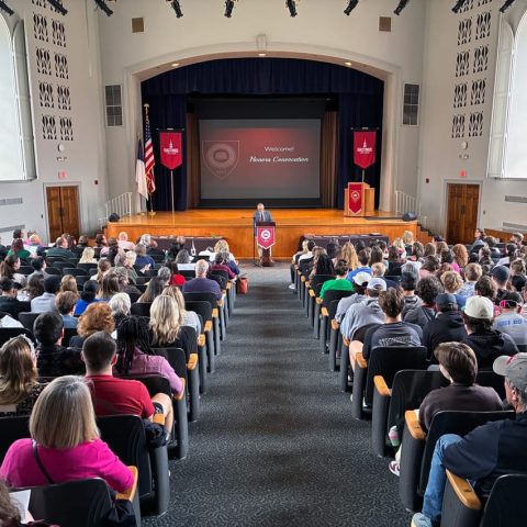 Photo of people sitting and the chapel stage.