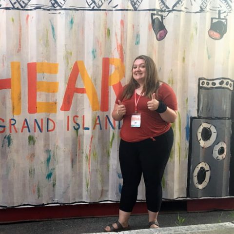 Student in front of a painted stage backdrop.