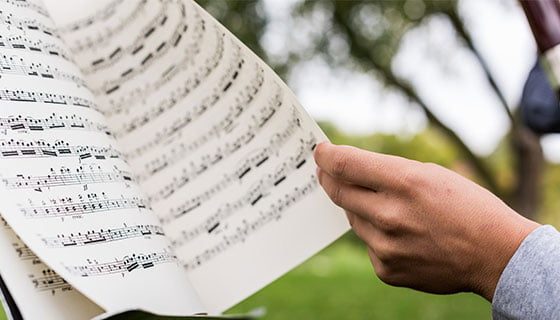 Student turning the page on some music on the Fuhr Hall lawn