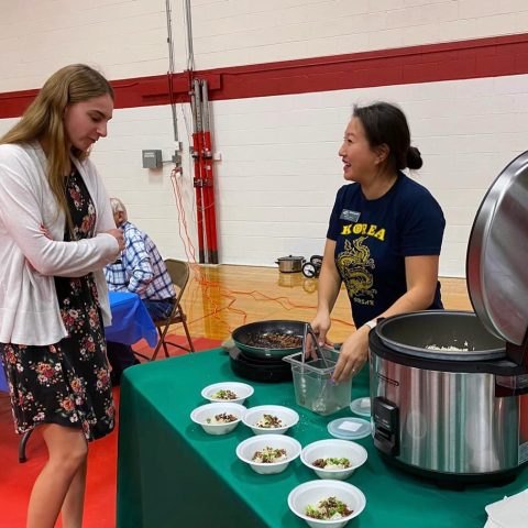 A festival attendee at a table featuring Korean food the 2024 Multicultural Festival.