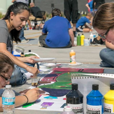 Students outside painting a mural.