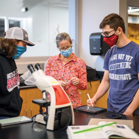 Dr. Amanda Solem, assistant professor of biology at Hastings College, works with students during lab. Students utilize college-provided iPads for completing lab handouts, drawing microorganisms, taking notes and tracking work.