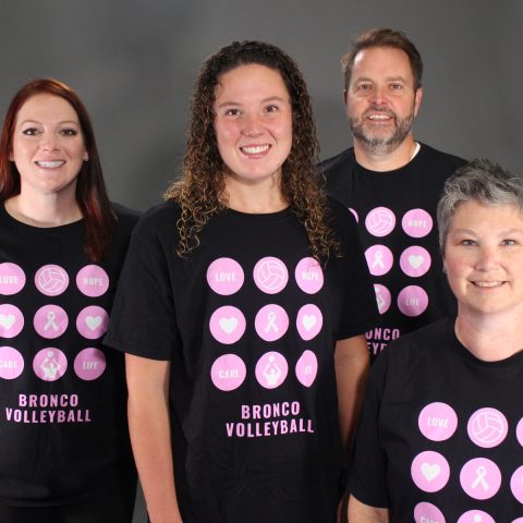 Modeling the 2022 Pink Night t-shirts are head volleyball coach Alex Allard; volleyball player Makenna Asher of Hastings, Nebraska; Chris Clements, athletic director; and Carissa Uhrmacher, assistant director of Career Services, who faced a breast cancer diagnosis in September 2021.