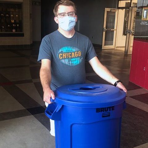 Hastings College junior Sam Johnson helps place new recycling bins during Dr. Neil Heckman's Environment Science Course.