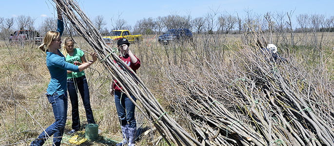 Hastings College graduate Teal Peterson helped gather sticks to construct art.